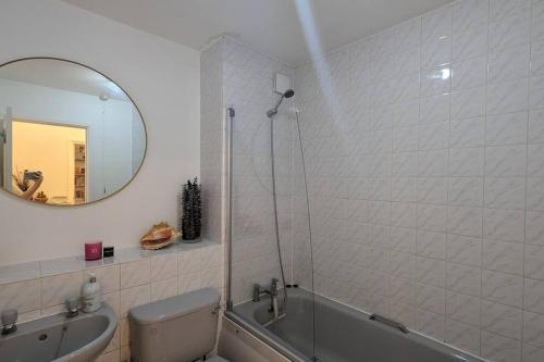 a bathroom with a tub and a sink and a mirror at Stylish, Peaceful 2-Bed Flat with Free Parking in New Barnet