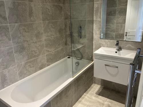 a bathroom with a tub and a sink and a shower at Splendid 2 Bed Flat with Private Terrace in Wimbledon - 2 The Queens in London