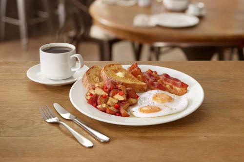 a breakfast plate with eggs bacon and toast and a cup of coffee at Four Points by Sheraton Orlando International Drive in Orlando