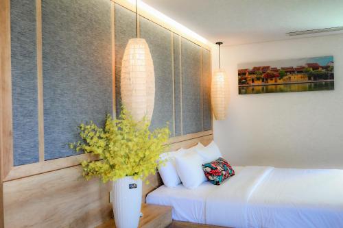 a bedroom with a bed and a vase of flowers at K House Apartment Danang Beach in Da Nang