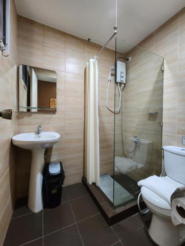 a bathroom with a shower and a toilet and a sink at Grayhouse Inn Tagaytay in Tagaytay