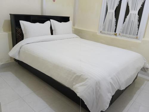 a bedroom with a large bed with white sheets and pillows at Balqis Homestay Syariah III Nagari Salo Kec Baso Kab Agam in Baso