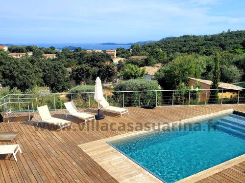 - une piscine sur une terrasse en bois avec des chaises et un parasol dans l'établissement Villa vue mer, piscine chauffée à Porto Vecchio, à Porto-Vecchio