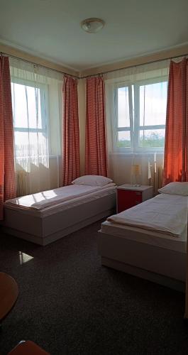 two beds in a bedroom with red curtains and windows at Sami Swoi Kutno in Kutno