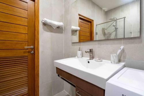 une salle de bains avec un lavabo blanc et un miroir dans l'établissement 1 bedroom apartment in Nai Harn, à Ban Saiyuan (1)