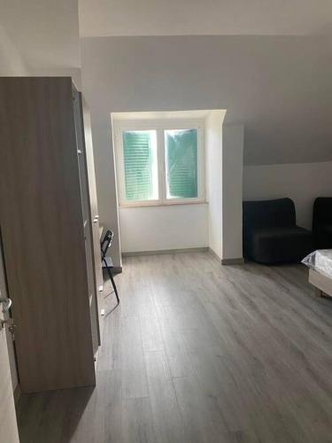 an empty living room with a couch and two windows at Camera Quadrupla Civitanova Marche in Civitanova Marche