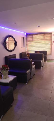 uma sala de espera com cadeiras azuis e um espelho em Hotel YURA y YANA em Quito