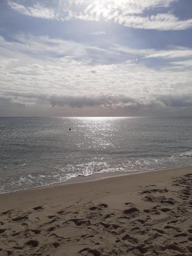 a beach with the ocean on a cloudy day at Dar louzir à Tazarka in Tazarka