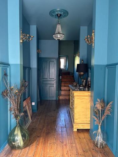 a hallway with blue walls and a wooden floor with vases at Moulin de Joumard, chambres et table d'hôtes de charme , jacuzzi, sauna, piscine et bain nordique 