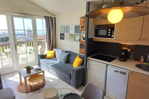 een keuken en een woonkamer met een bank en een tafel bij "FENÊTRE SUR MER" Appartement vue mer, 4 personnes, accès parc aquatique in Saint-Jean-dʼOrbetiers