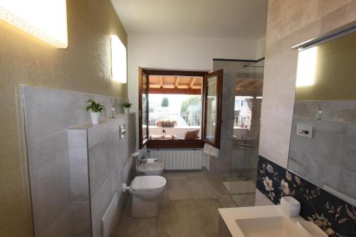 La salle de bains est pourvue de toilettes, d'un lavabo et d'une fenêtre. dans l'établissement Casa Nicole, à Manerba del Garda