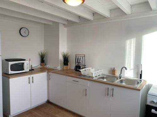 a white kitchen with a sink and a microwave at Bel appartement confortable avec jardin sur Cussac in Cussac-Fort-Medoc