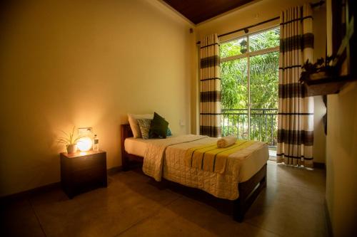 a bedroom with a bed with a lamp and a window at Evergreen Hotel Dambulla in Dambulla