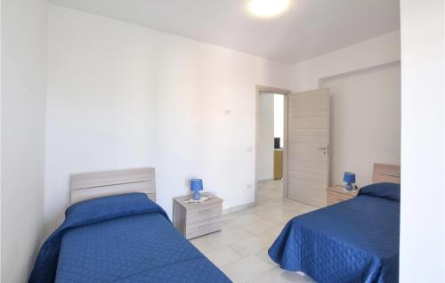 2 Betten in einem weißen Zimmer mit blauer Bettwäsche in der Unterkunft Amazing Apartment In Nicotera Marina With Wifi in Nicotera Marina