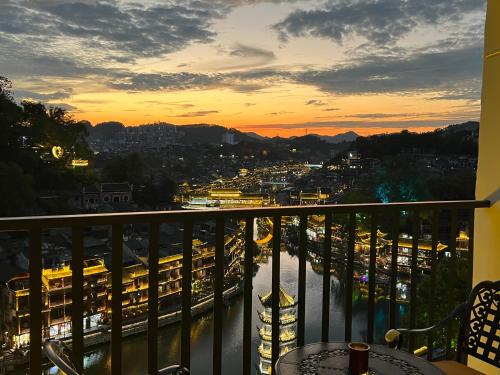 a balcony with a view of a city at sunset at Phoenix Best River View B&B in Fenghuang