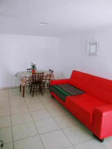 a living room with a red couch and a table at Habitación con baño y cocina compartido-Porto da Barra in Búzios