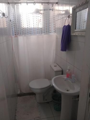 a white bathroom with a toilet and a sink at Habitación con baño y cocina compartido-Porto da Barra in Búzios