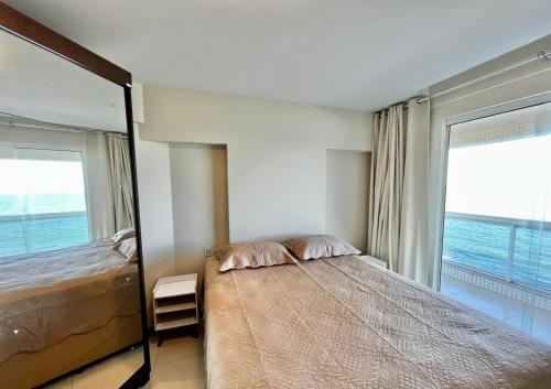 um quarto com uma cama e uma grande janela em Apartamento Frente Mar em Vila Velha