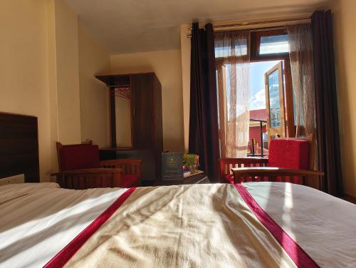 a bedroom with a bed and a window with chairs at Hotel The Narayani Continental in Gangtok
