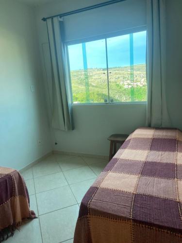 Cette chambre comprend deux lits et une grande fenêtre. dans l'établissement Excelente Casa em Diamantina com Vista para Serra, à Diamantina