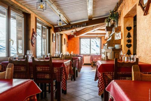 a restaurant with red tables and chairs and windows at Hotel Spa L'Equipe in Molines-en-Queyras