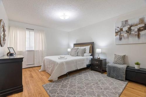 ein weißes Schlafzimmer mit einem Bett und einem Teppich in der Unterkunft COZY 2BR with Balcony and Parking Near NLRHC in Fort McMurray