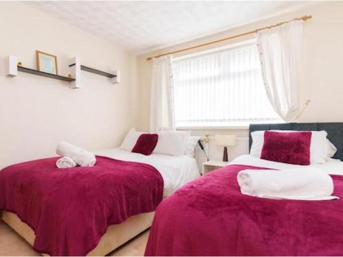 two beds in a room with purple blankets at Alexander House Apartments in Leeds