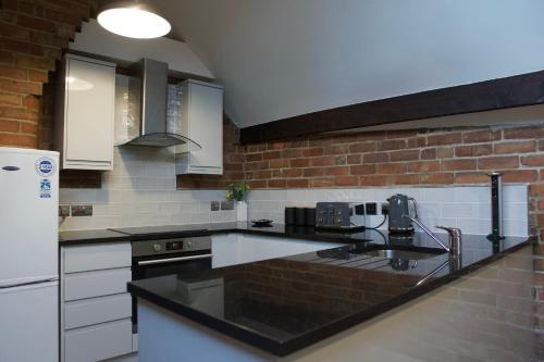 cocina con encimeras negras y pared de ladrillo en Luxury Penthouse In Central Nottingham, en Nottingham