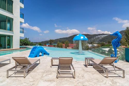 a swimming pool with chairs and a water slide at OCEANA HOME Phuket Kamala in Phuket Town