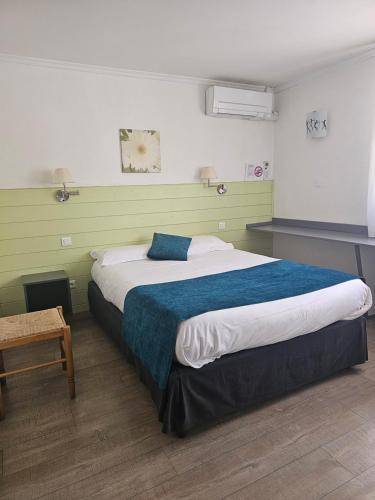 a bedroom with a large bed with a blue blanket at Hôtel Restaurant du Lac in Graulhet