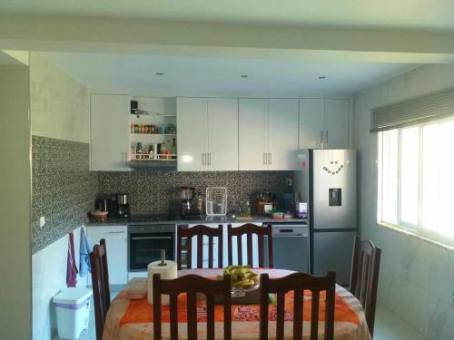 a kitchen with a table with chairs and a refrigerator at Bentub home in Ribeira Grande