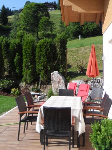 a table with chairs and an umbrella on a patio at Appartementhaus Casamarai in Saalbach Hinterglemm