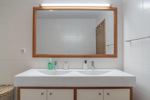 Apartment 7 on Paul do Mar Beach في بول دو مار: حمام مع حوض أبيض ومرآة