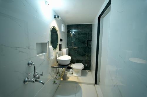 a white bathroom with a toilet and a sink at Shangri-La Villa Kumbhalgarh in Kelwāra