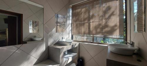 a bathroom with a sink and a toilet and a window at THE POT AIRBNB, FAERIE GLEN, PRETORIA EAST in Pretoria