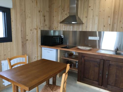 une cuisine avec une table en bois et un micro-ondes dans l'établissement Le clos saint Jean, à Dragey-Ronthon