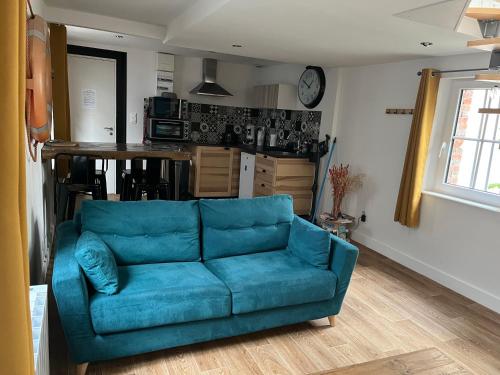 - un canapé bleu dans un salon avec une cuisine dans l'établissement Moana, à Honfleur