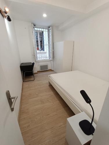 Cette chambre blanche comprend un lit et un bureau. dans l'établissement T3 rénové avec cour, Intra Muros Avignon, à Avignon