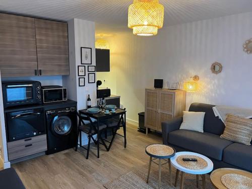 ein Wohnzimmer mit einem Sofa und einem Tisch in der Unterkunft Studio confortable aux portes de Bordeaux et Médoc in Ludon-Médoc