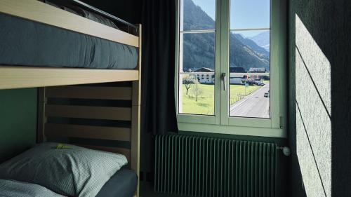 a bedroom with a bunk bed and a window at Hotel Alpina Einhorn - Self-Check-In in Wolfenschiessen