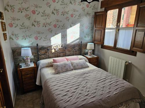 Un dormitorio con una cama con almohadas rosas. en El Rincón del Oteru, en Llanes