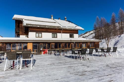 a large building with chairs in the snow at Hotel Spa L'Equipe in Molines-en-Queyras