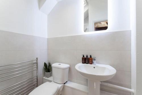 Baño blanco con aseo y lavamanos en Cosy & Peaceful Self Contained Home in Montpellier en Cheltenham