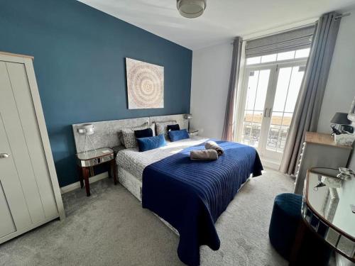 a bedroom with blue walls and a bed with blue sheets at Luxury on the beach in Portsmouth