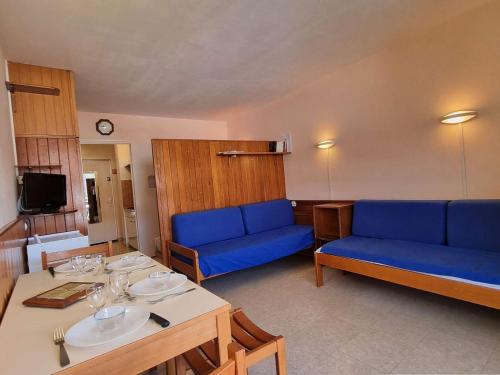 un salon avec des canapés bleus et une table dans l'établissement Studio cosy 4 pers avec terrasse, proche pistes et commerces - FR-1-525-261, à Saint-Étienne-en-Dévoluy