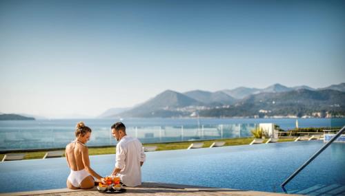a man and a woman sitting next to a pool at Dubrovnik President Valamar Collection Hotel in Dubrovnik