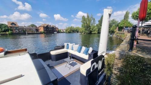 - un bateau sur une rivière avec des chaises dans l'établissement The Royal Escape Windsor, Static Wide Beam Barge, à Eton
