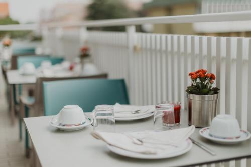 a table with plates and glasses and a vase of flowers at Hotel Bellavista in Grado