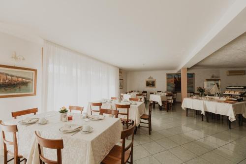 Hotel Bellavista في غرادو: غرفة طعام مع طاولات وكراسي بيضاء