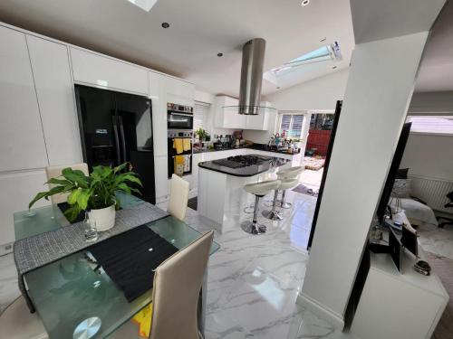 a kitchen with a glass table and white cabinets at West Dulwich Home 28 Mins to London Victoria in London